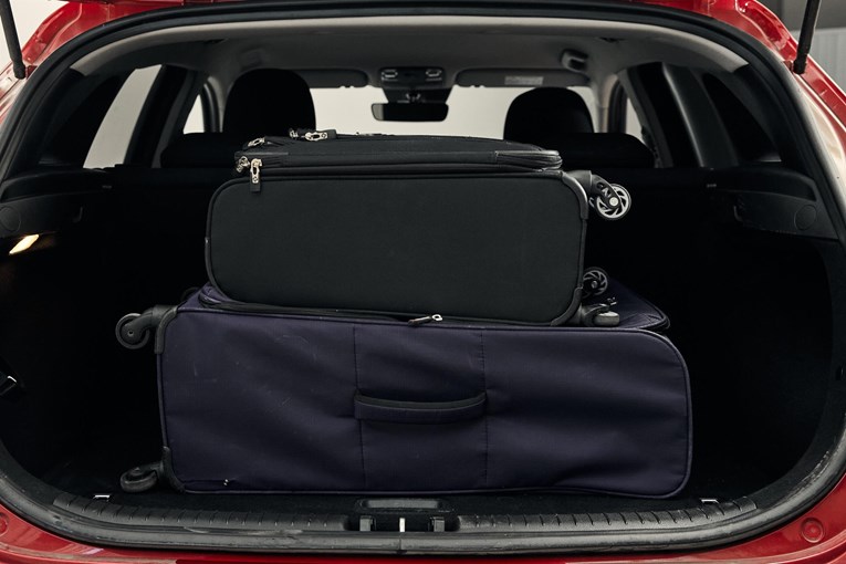 Red Kia Ceed with open trunk and luggage. 